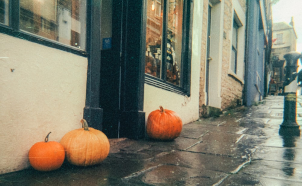 a couple of pumpkins sitting on the side of a building