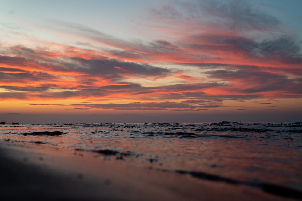 a sunset on a beach with waves coming in