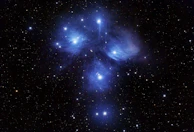 Close-up of a bright star cluster glowing vividly against the dark space.