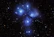 Close-up of a twinkling star cluster softly illuminating a serene, cosmic blue background.