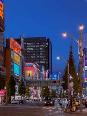 Technician installing a large illuminated sign on a busy city street at dusk.