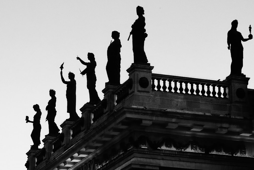 a black and white photo of statues on top of a building