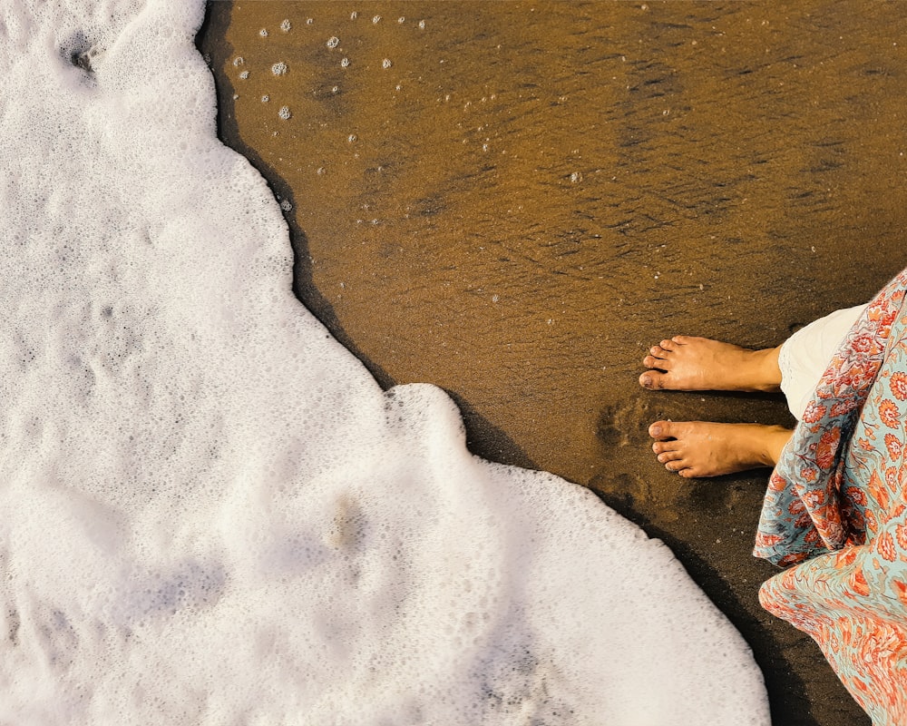 a person laying on top of a sandy beach next to the ocean