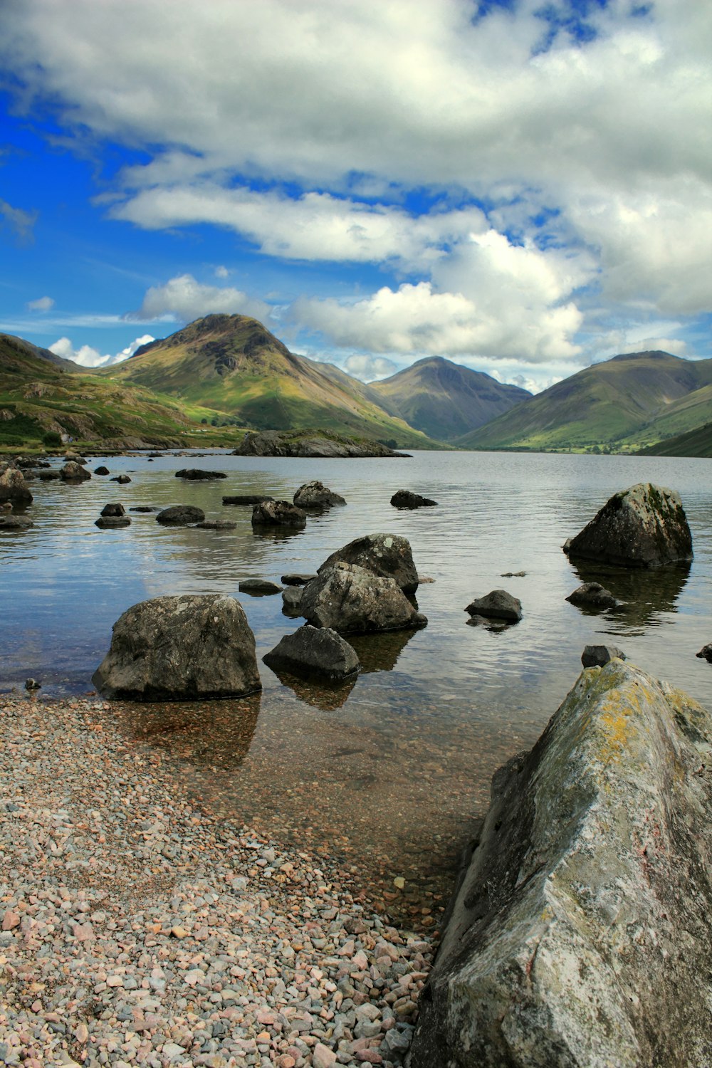 a lake surrounded by mountains under a cloudy sky