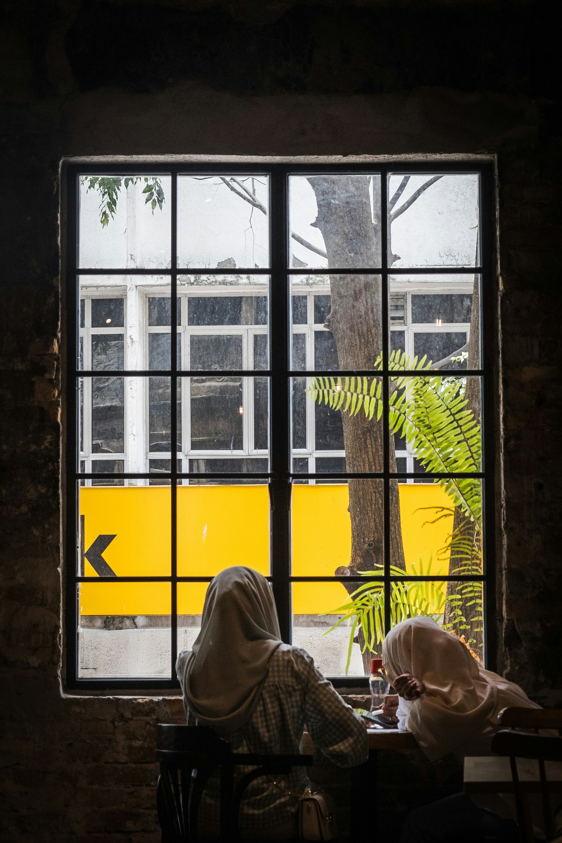 a woman sitting at a table in front of a window