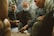 A group of adventurers gathered around a wooden quest board in a rustic setting, discussing their next mission.