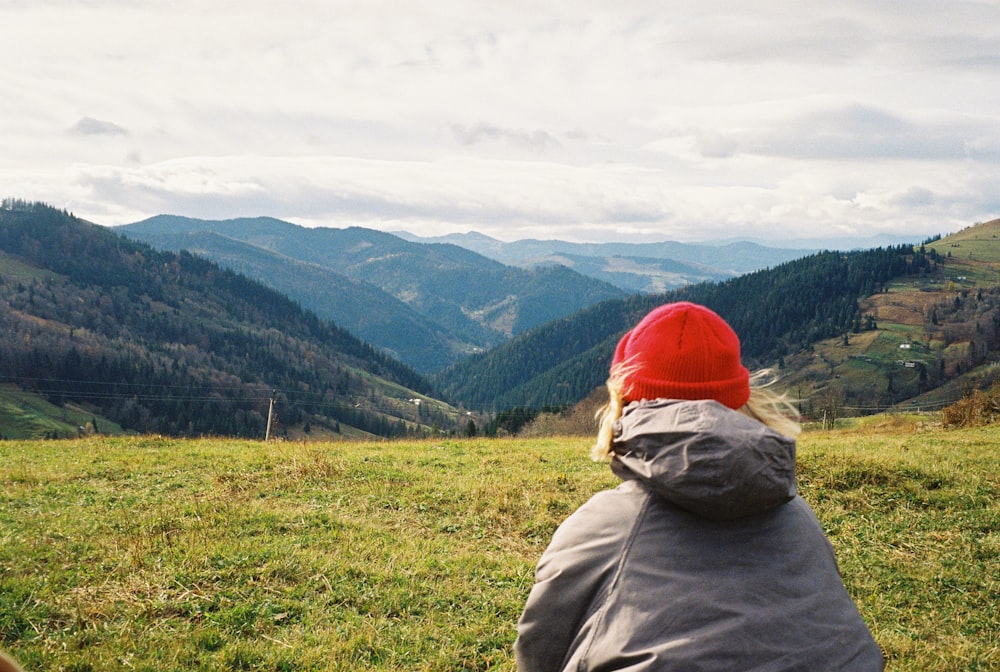 a person sitting in a field with mountains in the background