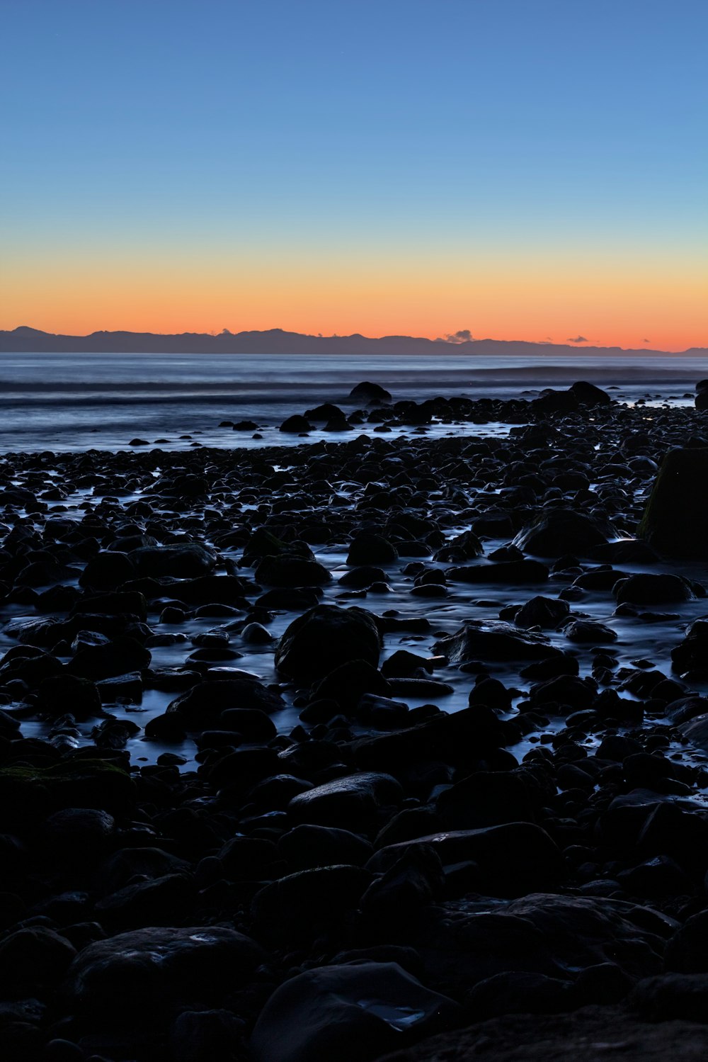 a person sitting on top of a rock covered beach