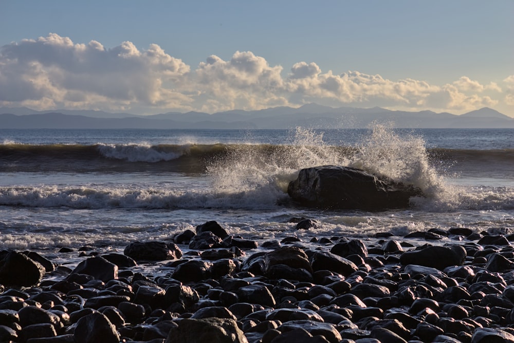 uma grande rocha sentada no topo de uma praia ao lado do oceano