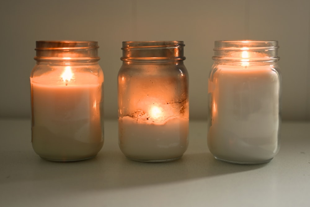 three jars filled with candles sitting on a table