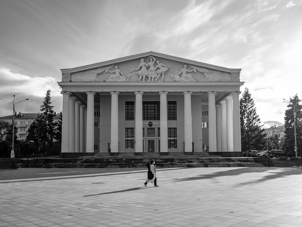 two people walking in front of a large building