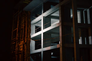 Evening shot of a partially completed building illuminated by construction lights, highlighting structural precision