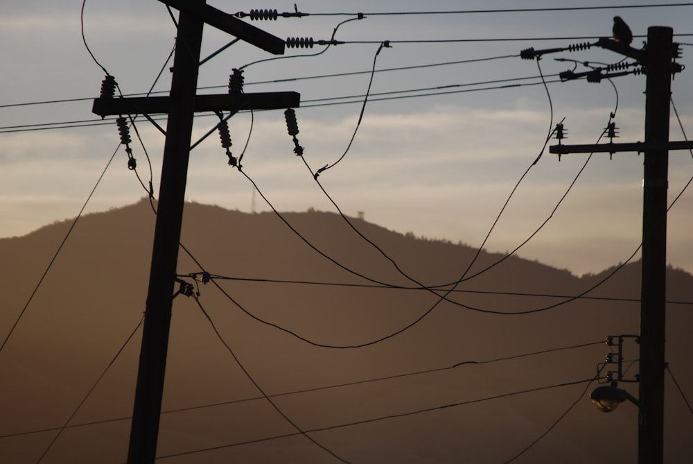 linhas elétricas e postes telefônicos com uma montanha ao fundo