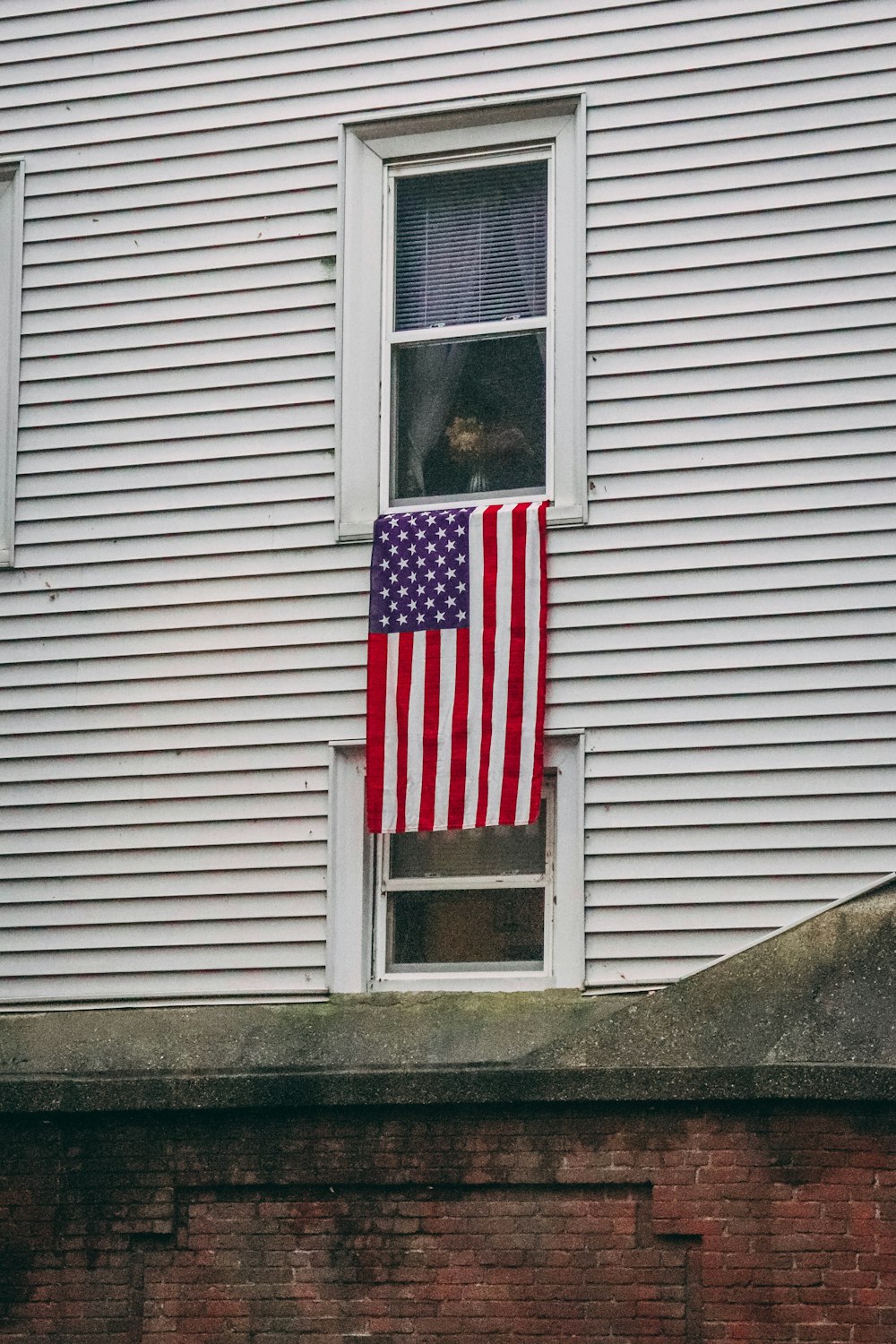 an american flag hanging in a window of a house