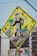 A street sign is heavily covered with a variety of colorful, overlapping stickers. The stickers feature numerous designs, including logos, graphics, and text such as 'BRUHA ONLY' and 'SK8 ONE'. The sign's original purpose is obscured, with stickers and graffiti adding a vibrant and eclectic aesthetic.