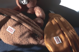 A stylish diaper bag placed next to a plush toy on a soft rug.