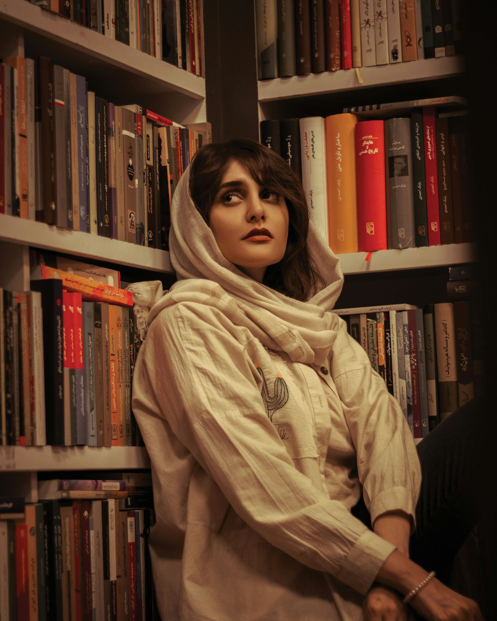 a woman sitting in front of a book shelf