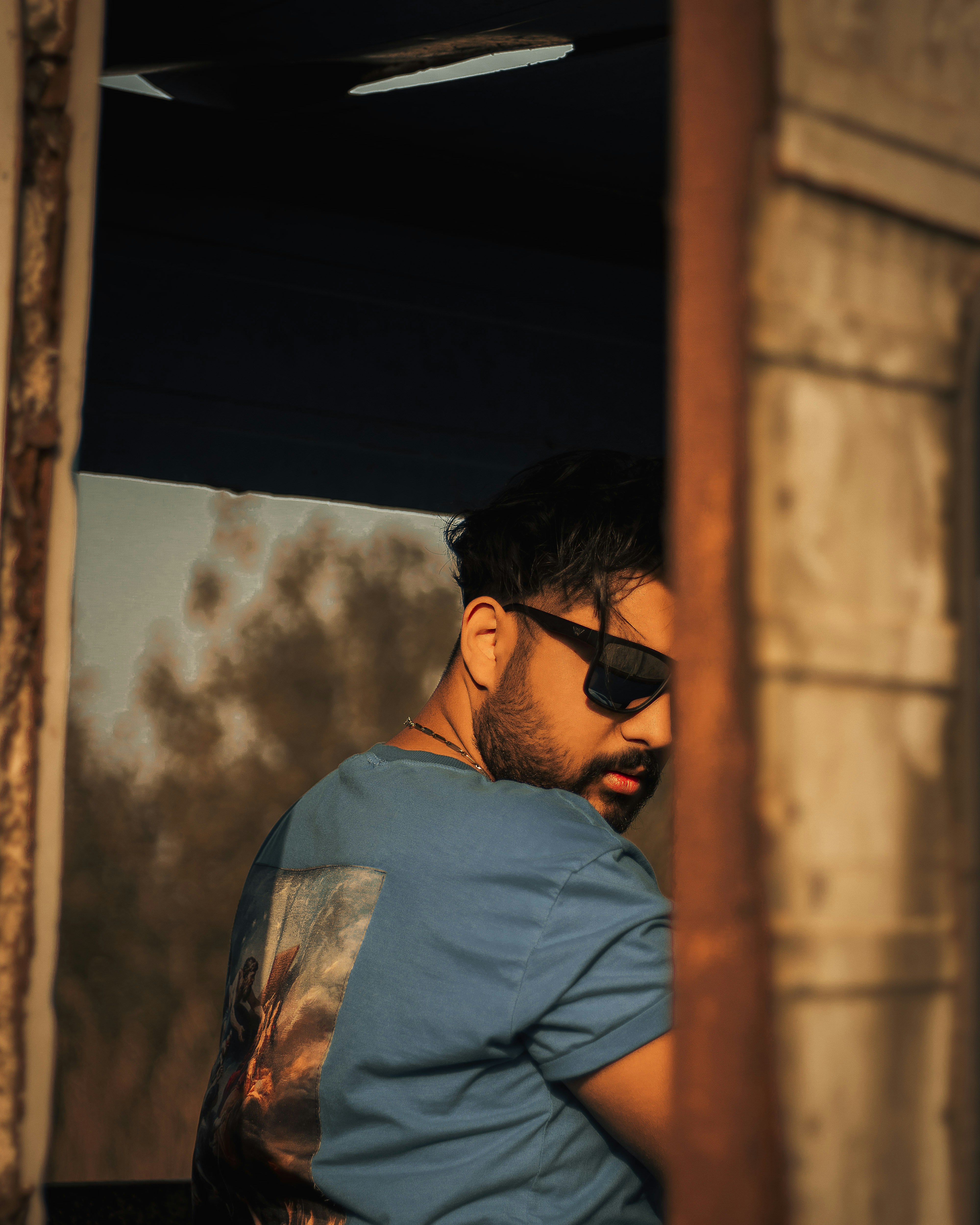 un uomo in camicia blu e occhiali da sole neri