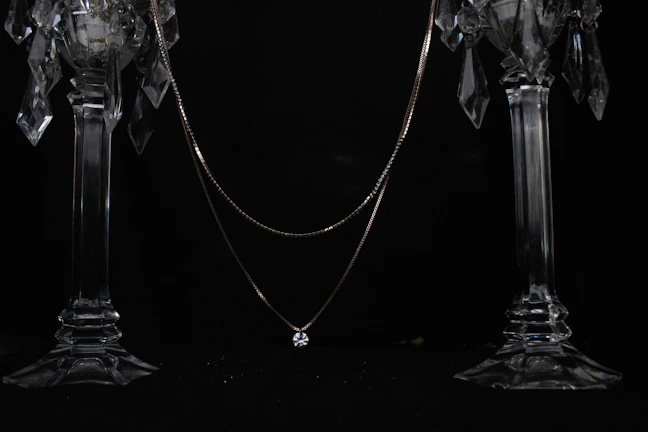 Artistic shot of a layered necklace with dark crystals reflecting soft candlelight.