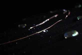 Close-up of a delicate gold necklace glowing softly against a warm, radiant background.