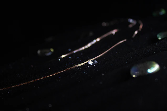 Close-up of a delicate 18k gold chain resting elegantly on black velvet, reflecting soft golden light.