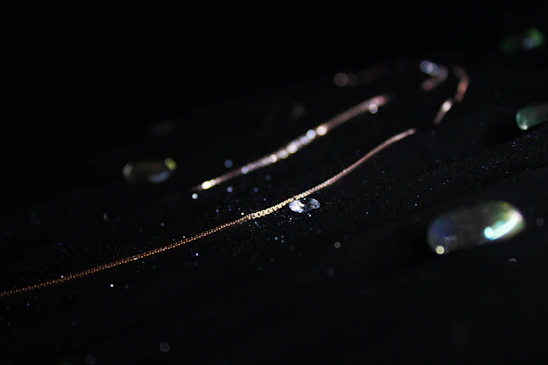Close-up of a delicate gold necklace glowing softly against a warm, radiant background.