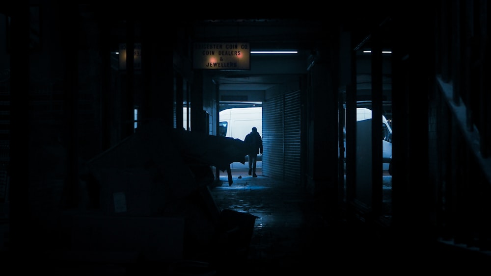 une personne debout dans un couloir sombre avec un cheval