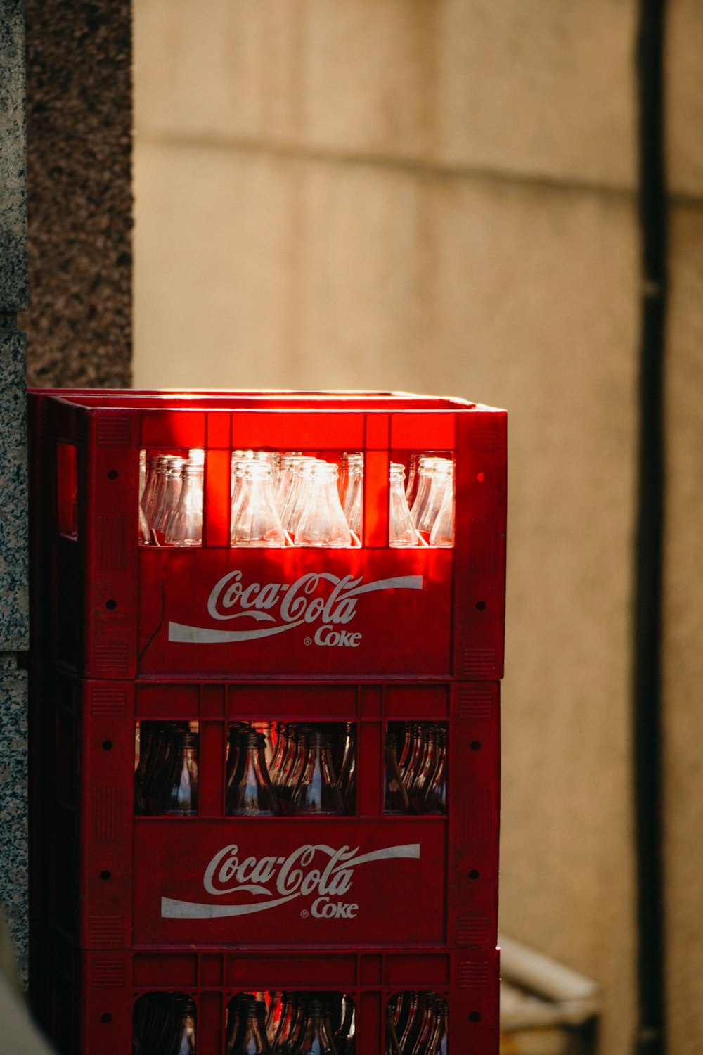 a red coca - cola machine sitting on the side of a building