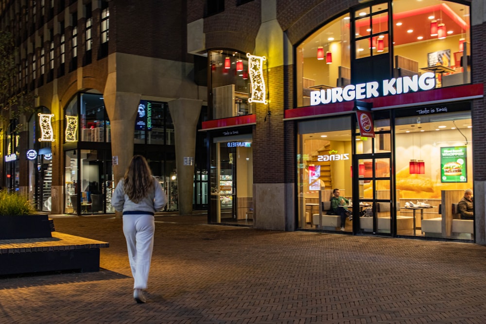 a woman walking past a burger king restaurant