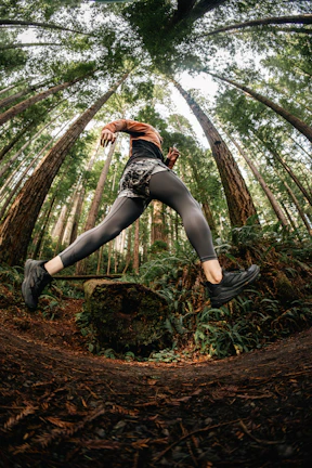 Action shot of a dusty trail winding through dense forest with runner's feet in frame
