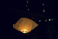 A softly glowing lantern floating upward into a starry night sky.