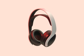 A pair of sleek, modern over-ear headphones with a white and black color scheme. The background is a solid peach color, which makes the headphones stand out prominently. The headphones have a cushioned headband and ear cups, with a red accent lighting adding a touch of elegance.