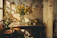 A sunlit guest room with rustic wooden furniture and fresh flowers on the bedside table.