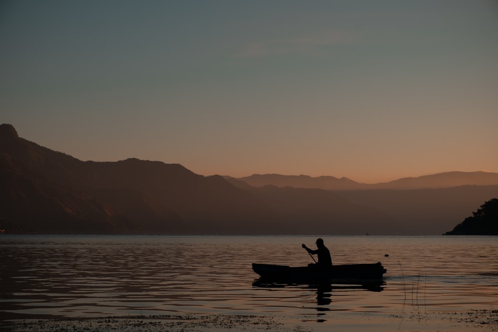 a person sitting in a small boat on a lake