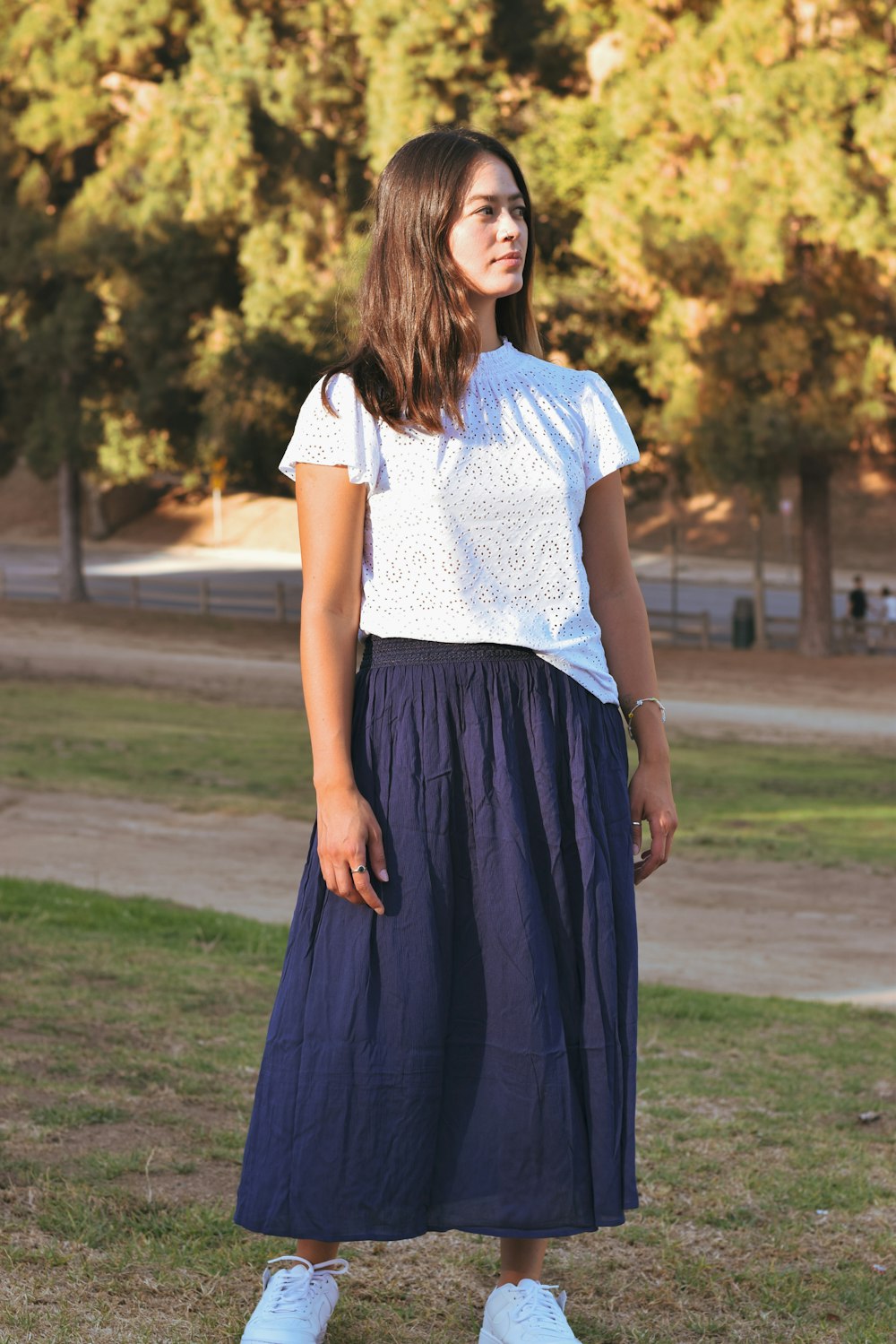 a woman standing in the grass wearing a skirt