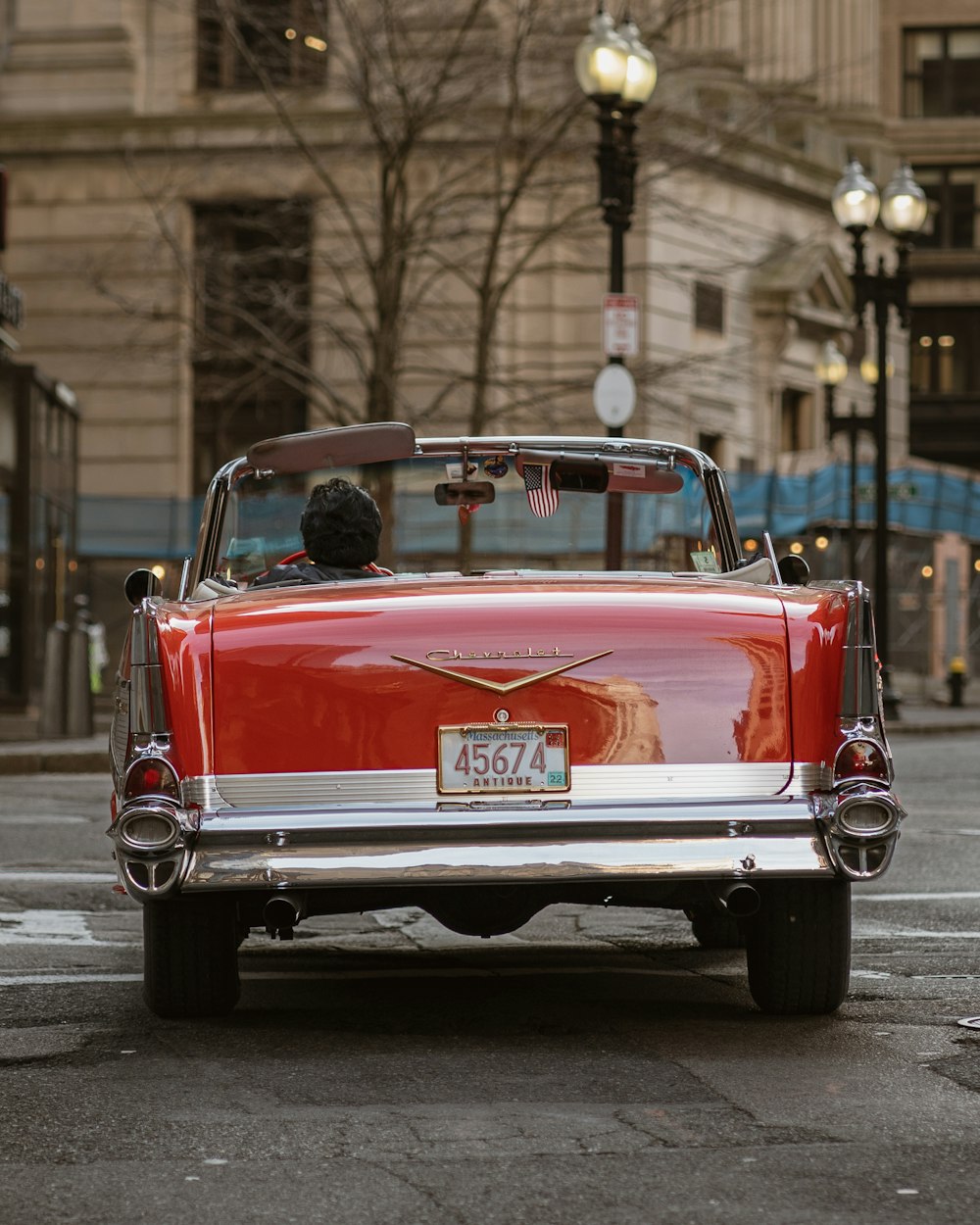 a red convertible car driving down a city street