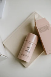 Natural deodorant containers surrounded by green leaves and flowers.
