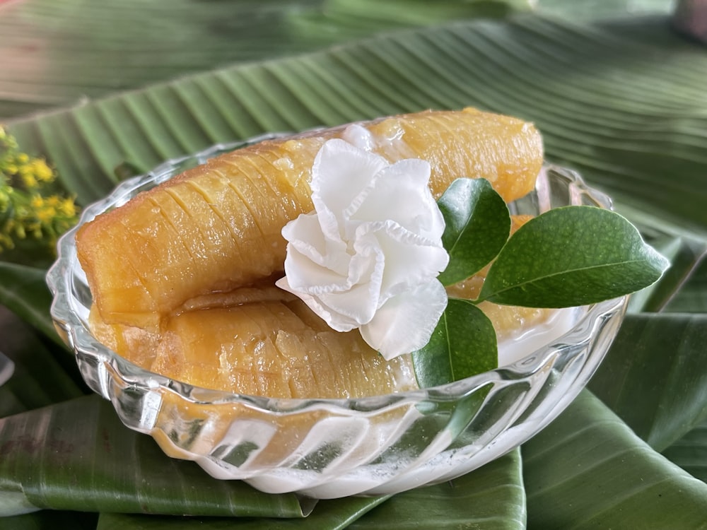 a glass bowl filled with fruit on top of a banana leaf