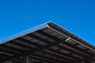 A technician inspecting a commercial metal roof under bright California skies.