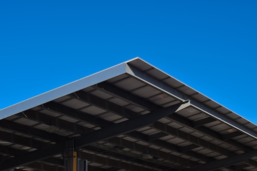 Newly built metal roof structure gleaming under a clear blue sky.