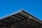 A large, angular metal roof structure set against a clear, vibrant blue sky. The roof features a grid-like pattern of beams and panels.