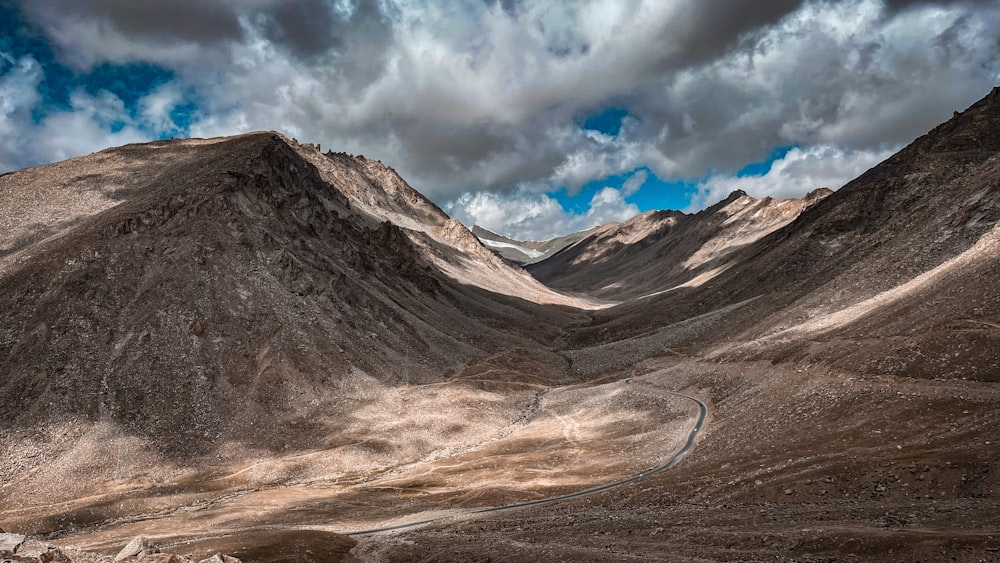 a mountain range with a winding road in the foreground