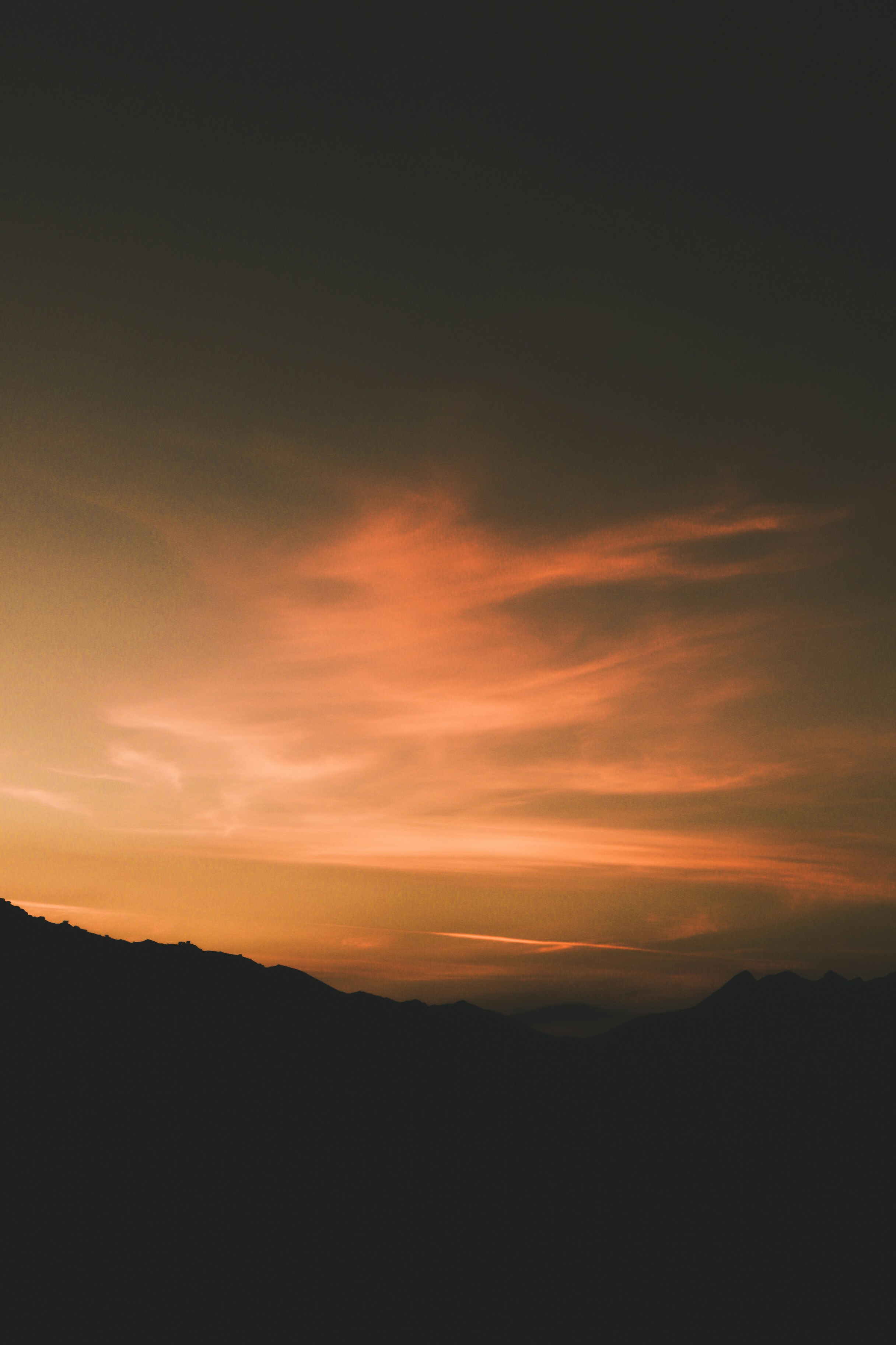 ein Flugzeug, das am Himmel mit einem Sonnenuntergang im Hintergrund fliegt