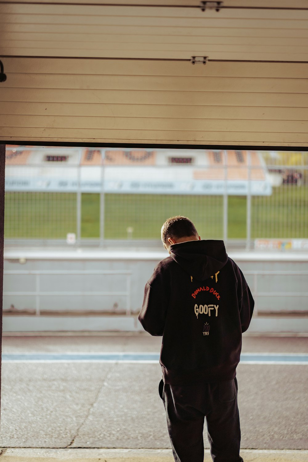 a man in a black hoodie is looking out a window