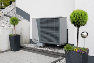 Close-up of a modern heat pump system installed outdoors with visible pipes and control panel.
