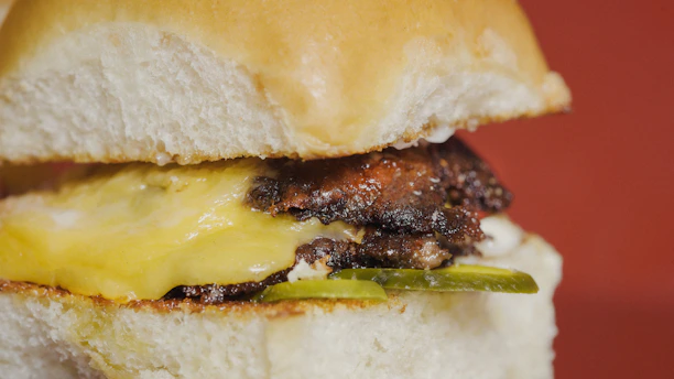 Close-up of a juicy, freshly grilled burger with melted cheese and crisp lettuce on a toasted bun.