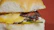 A close-up of a juicy smashed burger with melted cheese and fresh toppings, set against the warm, dark ambiance of the restaurant.