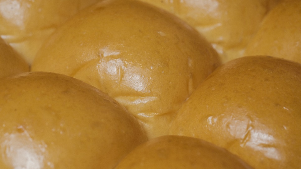 Close-up of freshly baked pão de queijo with a golden crust on a rustic wooden table.