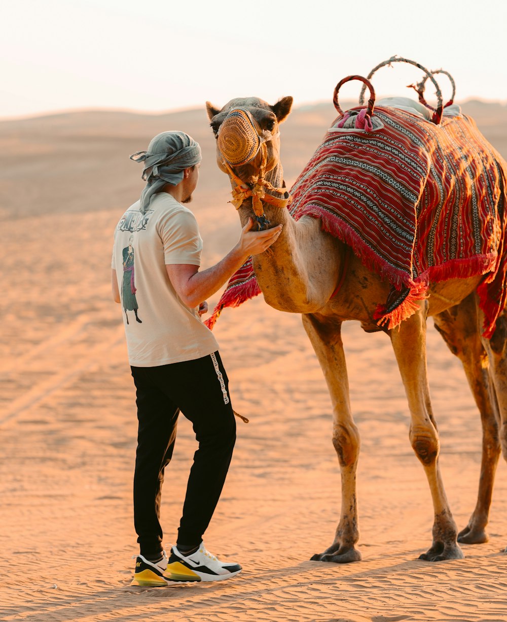 a man standing next to a camel in the desert