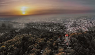 Aerial shot of a historic castle surrounded by lush greenery at sunset.